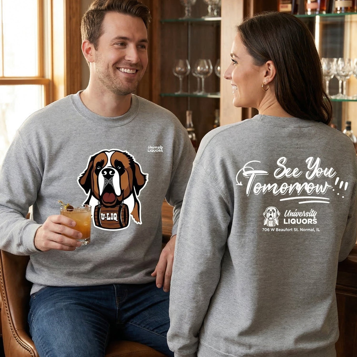 Two people wearing gray University Liquors sweatshirt, sitting in a bar setting.
