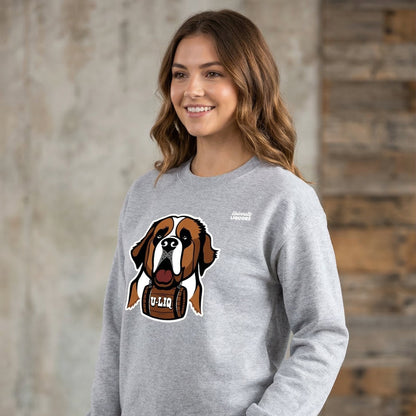 Woman wearing a gray University Liquors sweatshirt, standing against a stone wall.