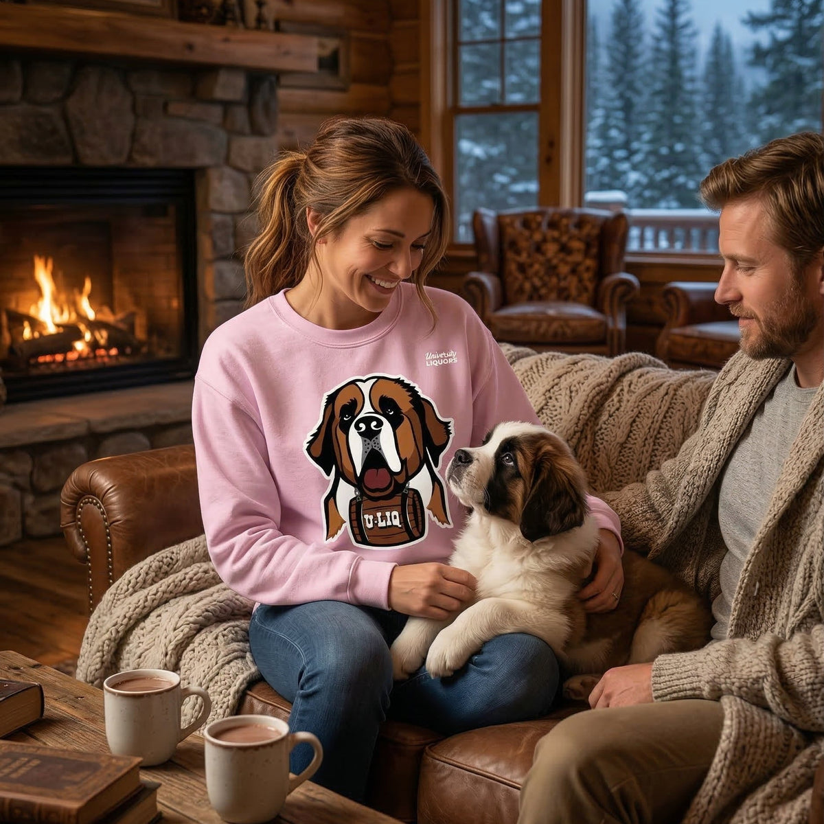 Woman in light pink University Liquors sweatshirt holding a puppy, sitting on a couch in a cozy living room.