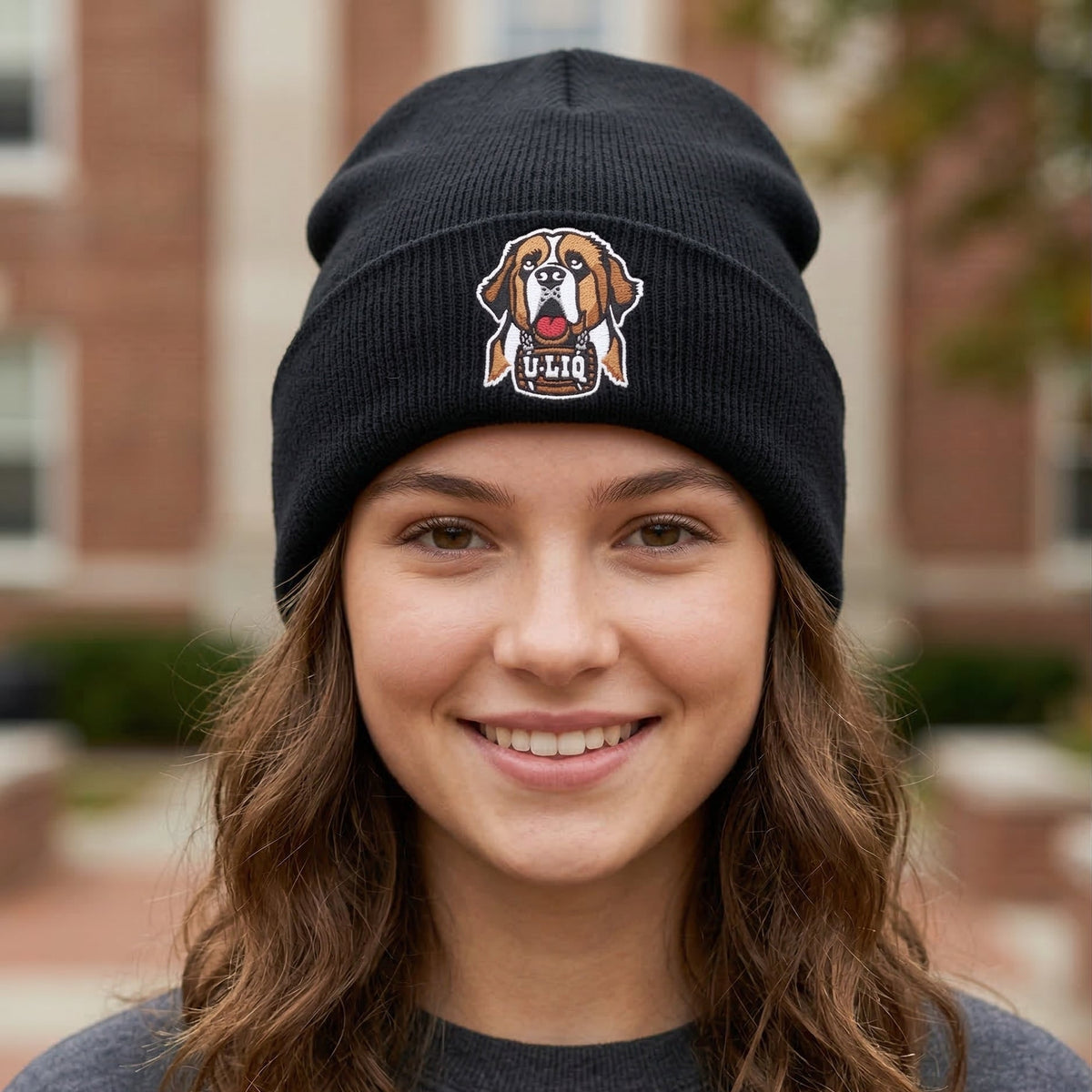Person wearing a black beanie with a University Liquors logo in front of a brick building