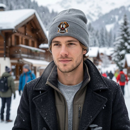 Man wearing a beanie with a University Liquors logo in a snowy village setting
