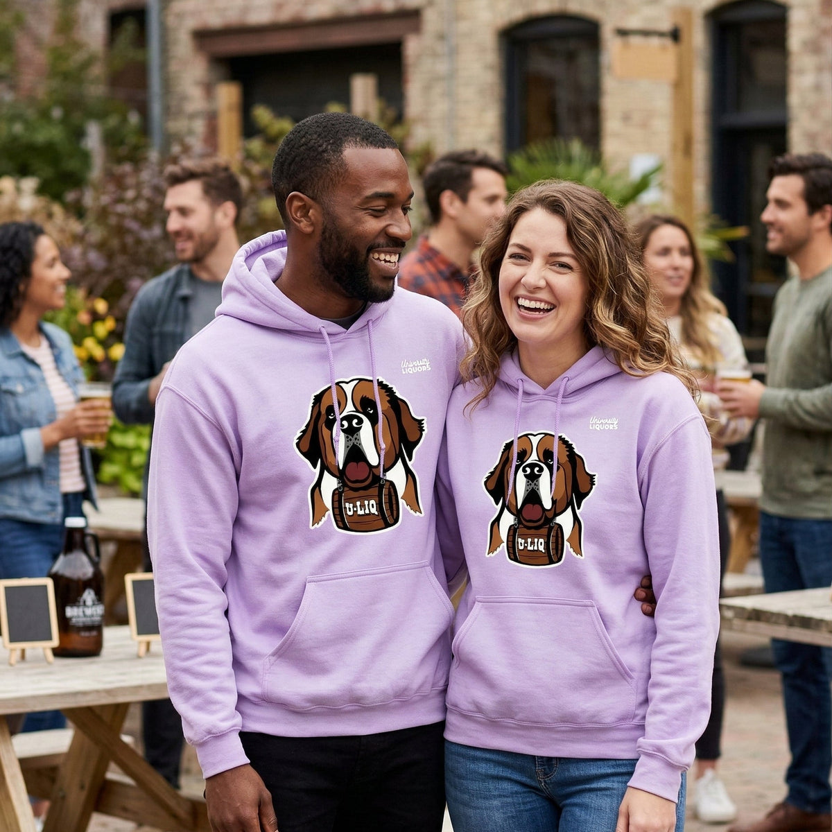 Two people wearing matching purple University Liquors hoodies with a dog graphic in an outdoor setting.