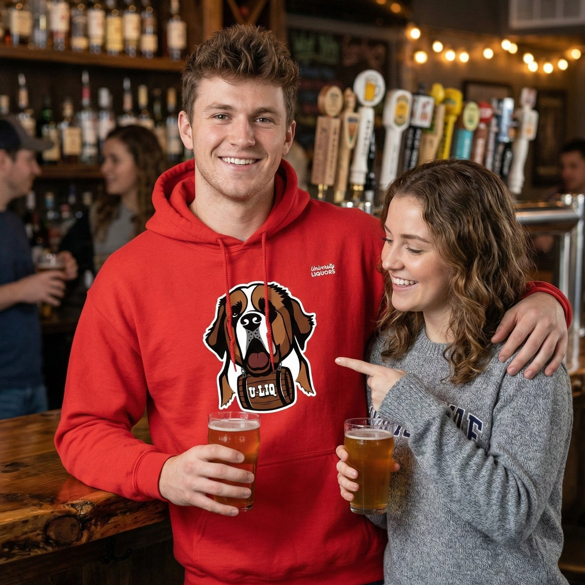 Two people in a bar, one wearing a red University Liquors hoodie.